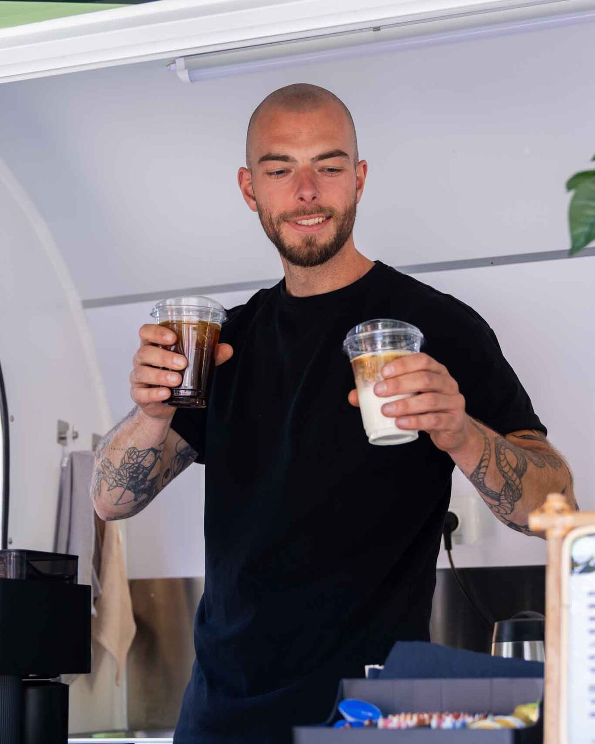 Barista van Joy of Coffee met twee iced coffees in de koffietrailer