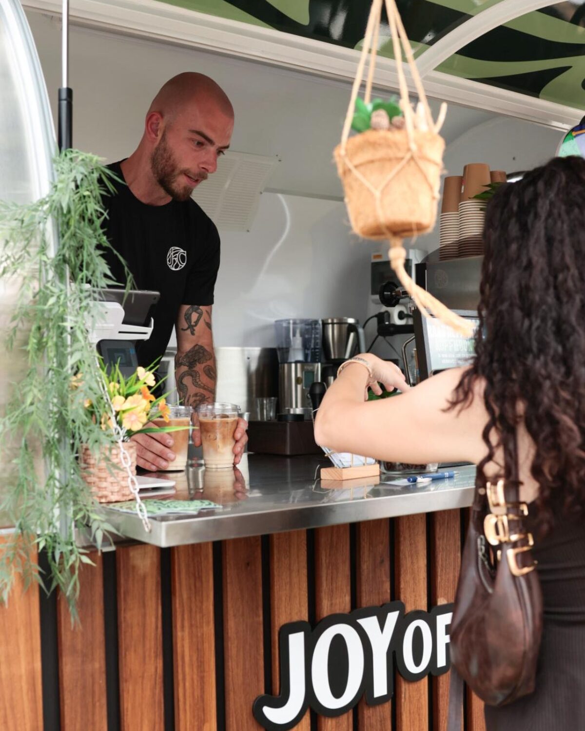 Barista serveert iced coffees vanuit de koffietrailer op een festival