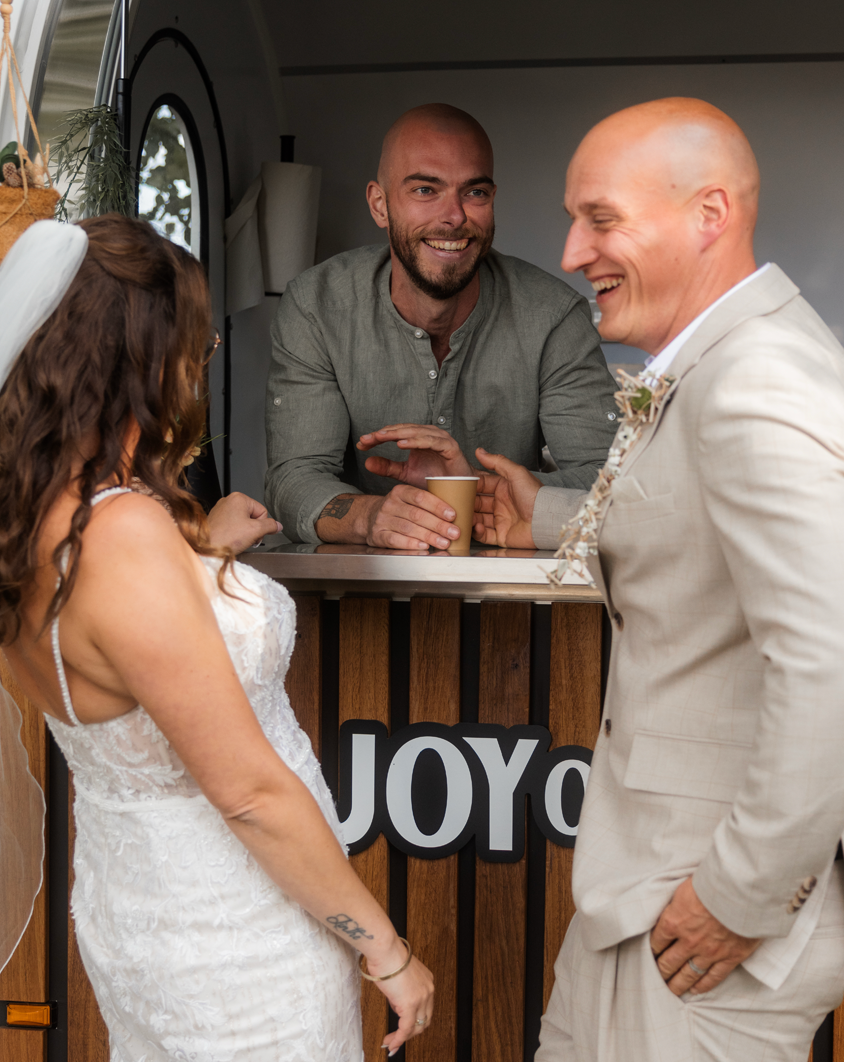 Joy of Coffee mobiele koffietrailer met barista die koffie serveert aan een bruidspaar op hun bruiloft