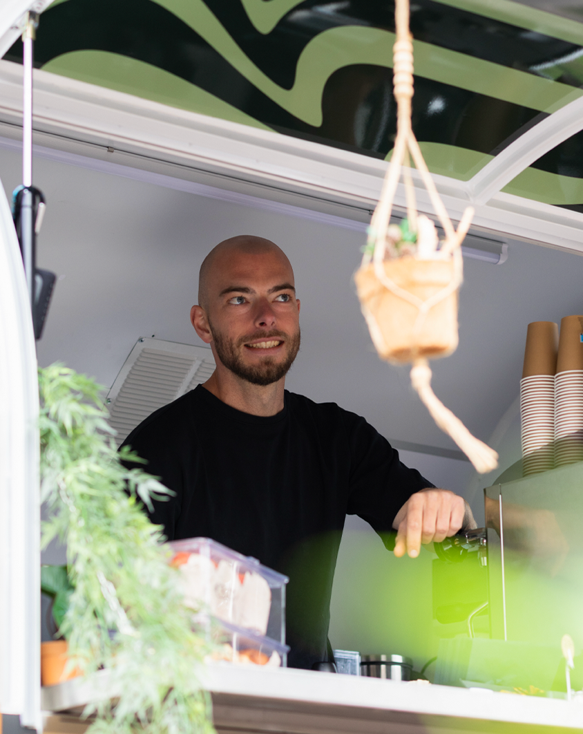 Barista van Joy of Coffee staat in stijlvolle mobiele koffietrailer op locatie, klaar in de koffiebar